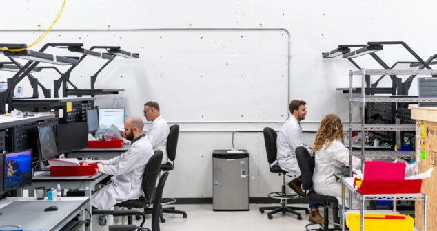 working with a contract manufacturer image of two rows of workers on assembly floor.