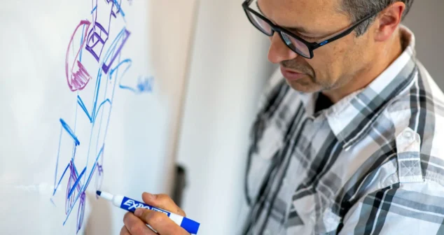 Engineer sketching early medical device concepts on a whiteboard during initial design exploration.