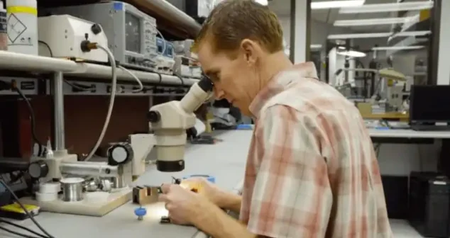 Engineer using a microscope for precision assembly of medical device components.