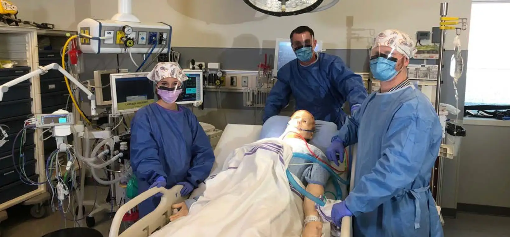 Clinical team in scrubs conducting simulated summative usability testing in a high-fidelity operating room environment with patient mannequin.