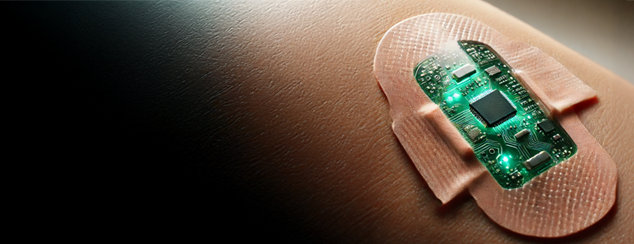 A close-up of a person's skin with a smart bandage applied. The bandage contains an embedded green-glowing electronic circuit, resembling a microchip, suggesting advanced medical monitoring or theranostic technology.